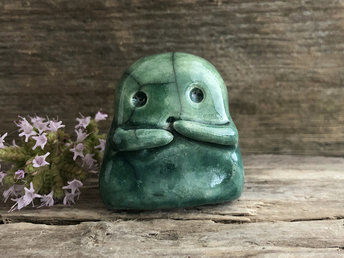 A sweet little kodama nature spirit ceramic guardian statue glazed in shades of green and with a lovely, gentle face and little arms.