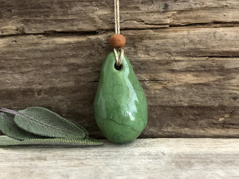 Raku ceramic worry pendant shaped a little like a bendy pear and glazed in green. It has a sandalwood bead above it and is strung on a flax cord.