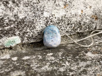 Simple ceramic Shinto Jizo pendant necklace in pale blue and white. Jizo has a kind, happy, and gentle face and is strung on an adjustable eco-hemp cord.