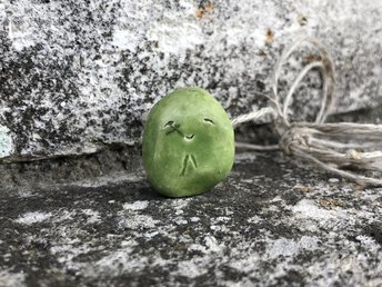 Simple raku ceramic Shinto Jizo pendant necklace glazed in spring green. Jizo has a kind, gentle face and is strung on a adjustable eco-hemp cord.