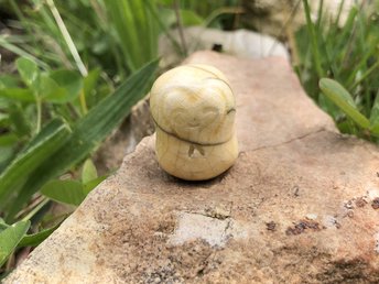 A smiley, loving, and gentle Jizo Shinto raku ceramic sculpture talisman glazed in pale yellow with a heart around his face.