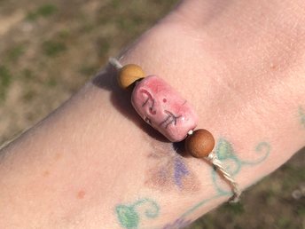 Pink raku ceramic cylindrical Shinto Jizo bead bracelet with two ethical sandalwood beads. It is strung on an adjustable eco-hemp cord. Jizo looks very happy and kind!