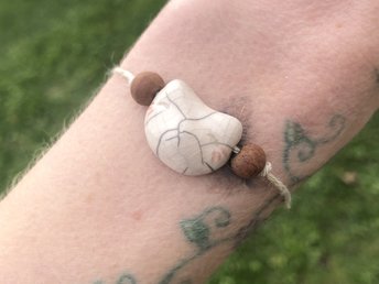 Sweet raku ceramic Inari kitsune fox-head bracelet on adjustable eco-hemp cord with two ethical sandalwood beds. This kitsune kami is white with red stripes by his grey eyes.