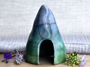 Raku spirit cave glazed in a bottom-to-top gradient of spring green to forest green to blue. It has a large, domed opening at its front.