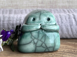 A sweet little kodama nature spirit ceramic guardian statue glazed in soft forest green and with a lovely, gentle face and little arms.