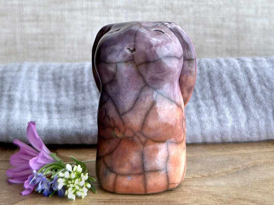 Raku ceramic usagi rabbit kami nature spirit glazed in a bottom-to-top gradient of warm red-orange to violet with hints of blue. Its ears are folded down its back, and it has a kind, gentle, smiling face.
