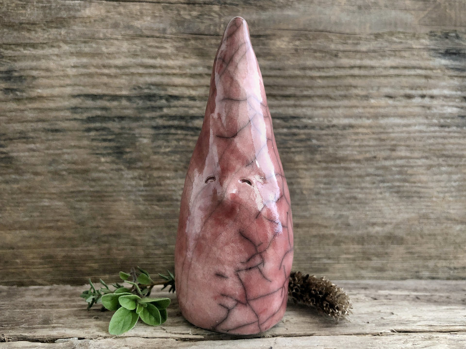 Raku ceramic sculpture of a tall, pointy gnome. He is very friendly and glazed in a warm, soft red colour.