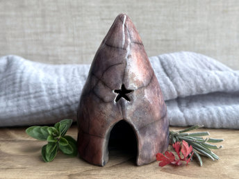 Raku spirit cave with with an arched door, a star window above it, and another window around the side. It's glazed in a variety of colours: soft warm orange, violet and purple, indigo, mauve, and soft deep red.